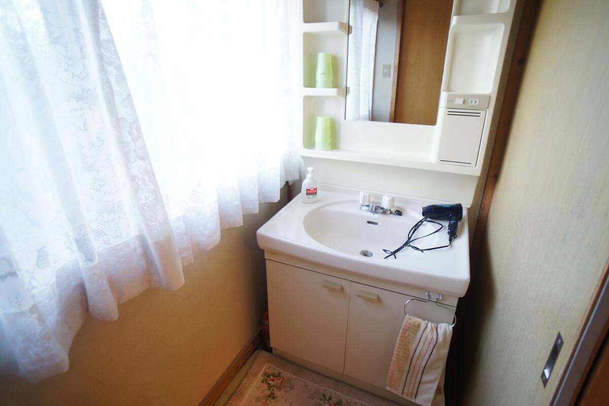 Een badkamer met een wit wastafel, een spiegel en een handdoekhouder.