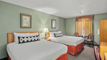 A hotel room with two beds, a desk, a chair, and a window with curtains.