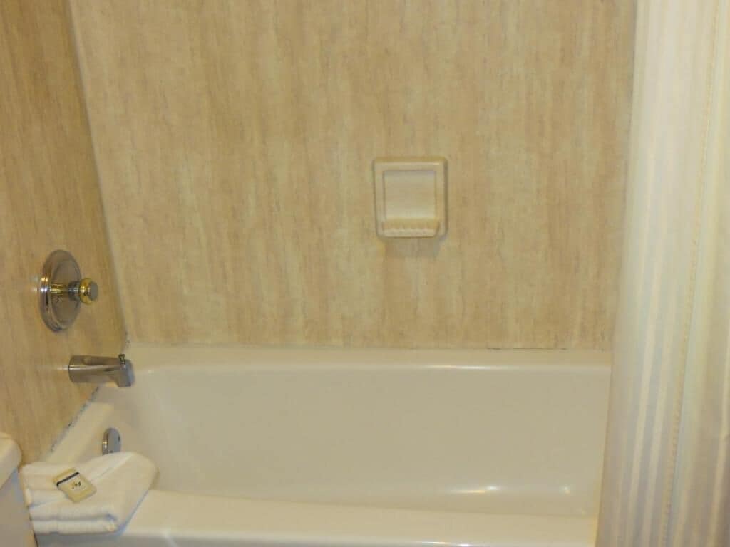 Un bagno con una vasca, un portascopino e un saponiero.