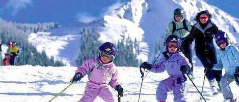 Eine Gruppe von Skifahrern auf einem verschneiten Hang, im Hintergrund Berge.