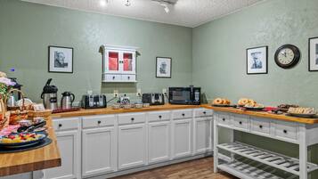 A kitchen with white cabinets, a wooden countertop, a coffee maker, a toaster, and a clock on the wall.