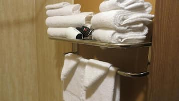 Een badkamer met een handdoekrek met netjes gevouwen witte handdoeken en een haardroger.