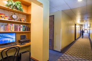 En hotellobby med en lång korridor, en receptionsdisk och en bokhylla med böcker och dekorativa föremål.