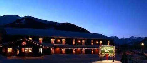 A snow-covered building with a sign reading "Old Town Inn" in a mountainous area at night.