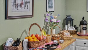 Una encimera de cocina con varios objetos, incluyendo cestas, una cafetera y un plato de fruta.