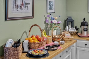 A kitchen counter with various items including baskets, a coffee maker, and a plate of fruit. - Old Town Inn (Crested Butte)
