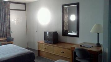 A hotel room with two beds, a desk with a lamp, a television, and a mirror.