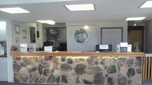 Una recepción con fachada de piedra, un televisor de pantalla plana y una cafetera.
