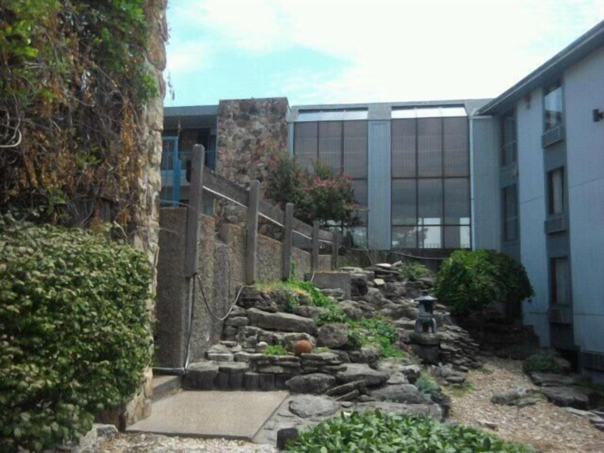 A stone pathway leading to a building with a modern facade and large windows.