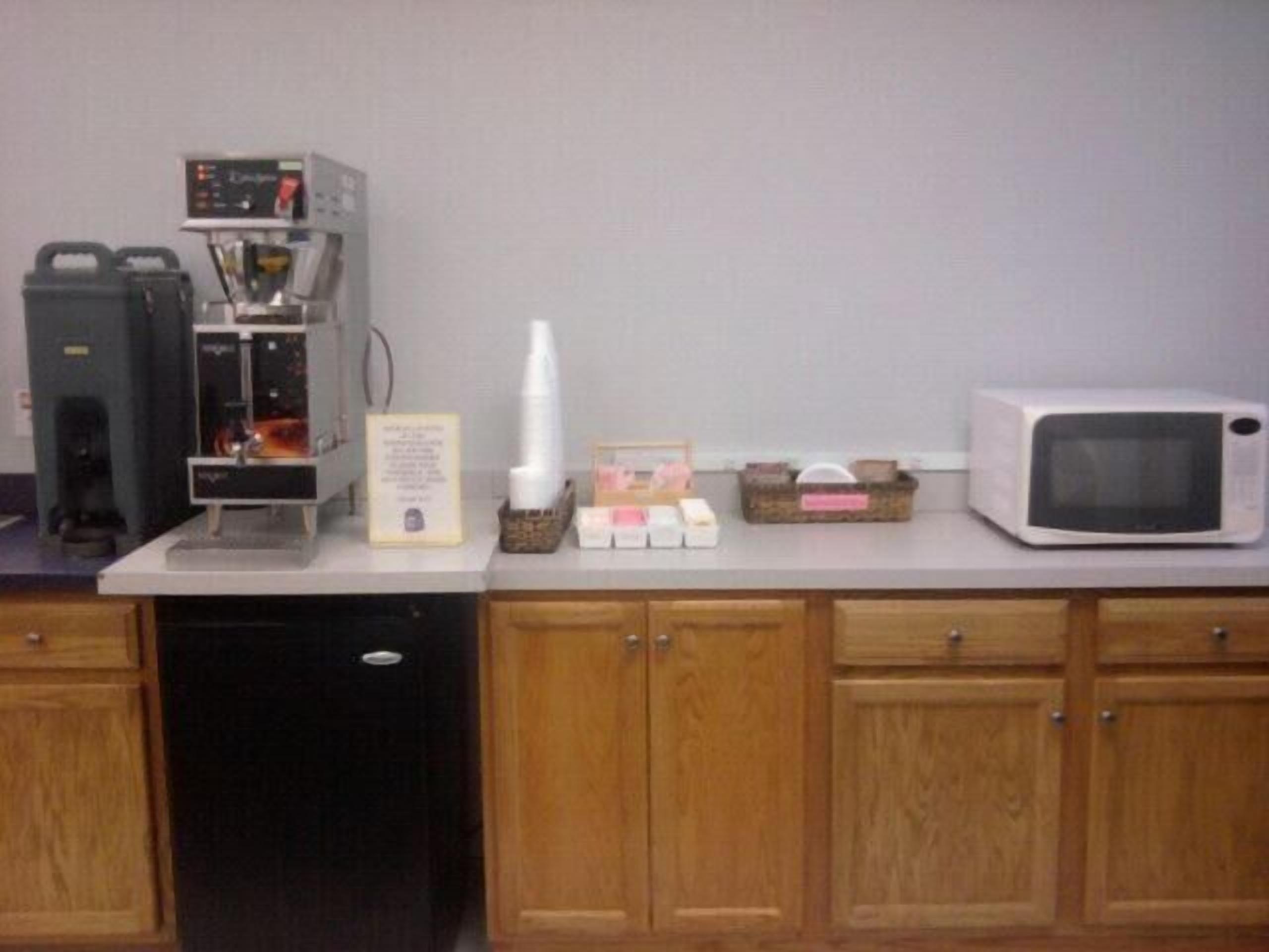 A kitchen with a coffee machine, microwave, and various kitchen items on the counter.
