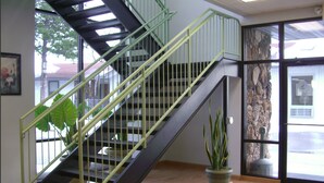 Una escalera con barandilla de metal, una planta en maceta y una pared de piedra.