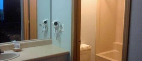 A bathroom with a sink, mirror, toilet, and shower.