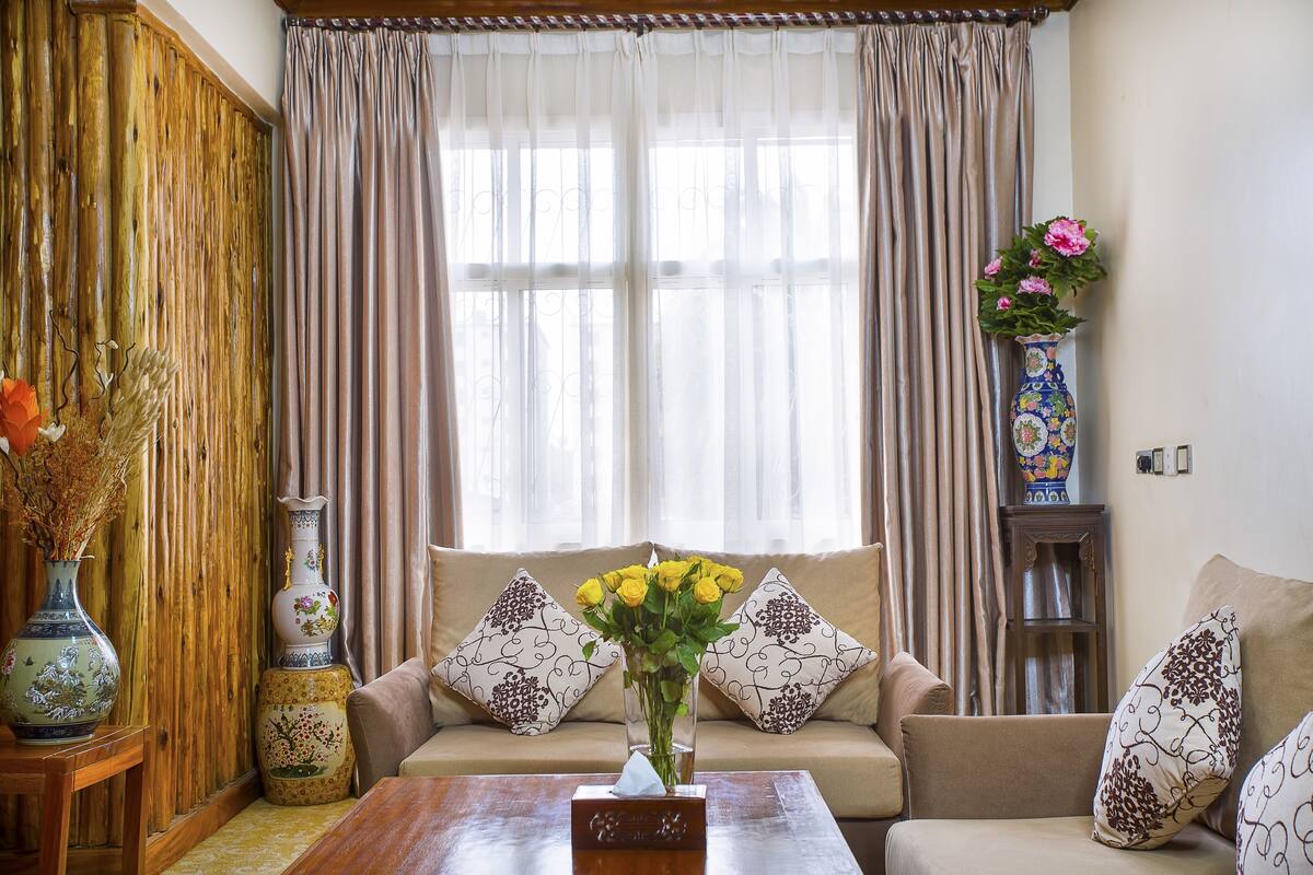 A living room with a sofa, two decorative vases, and a table with a tissue box.