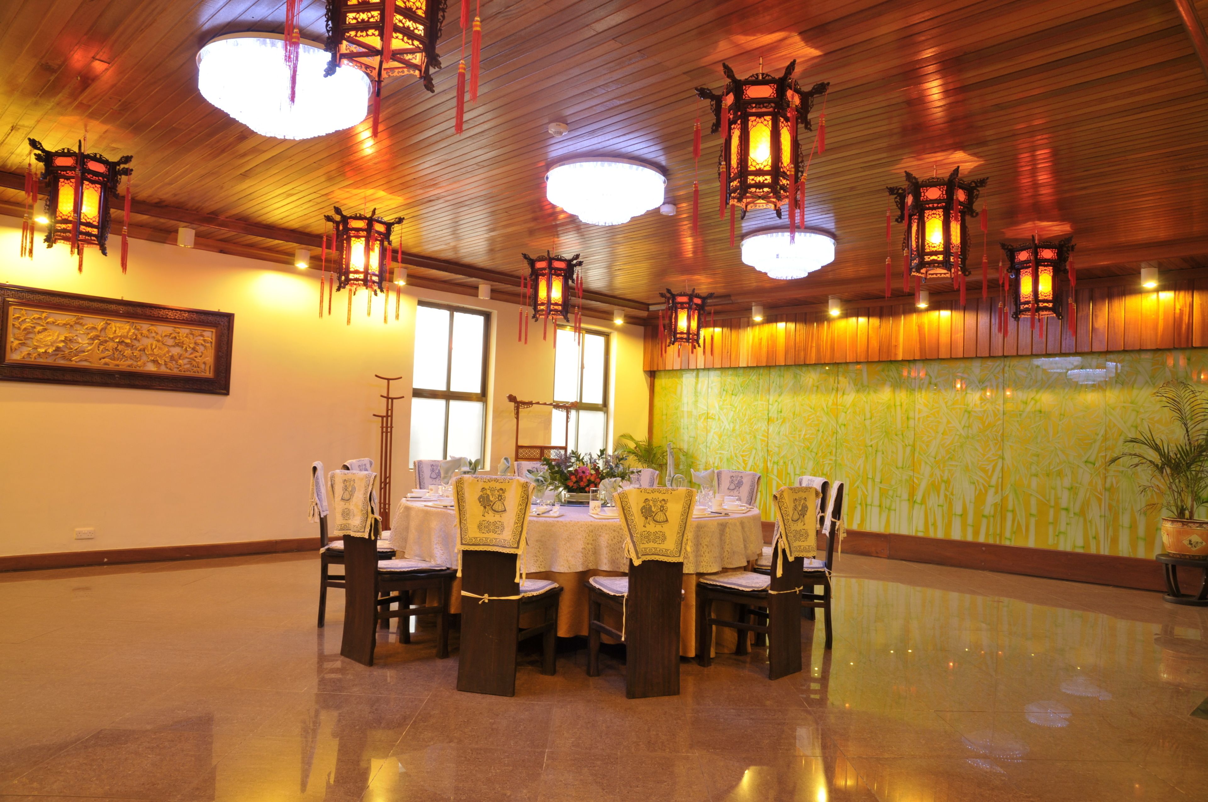 A dining area with round tables, chairs, and hanging lanterns.