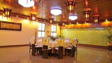 A dining area with round tables, chairs, and hanging lanterns.