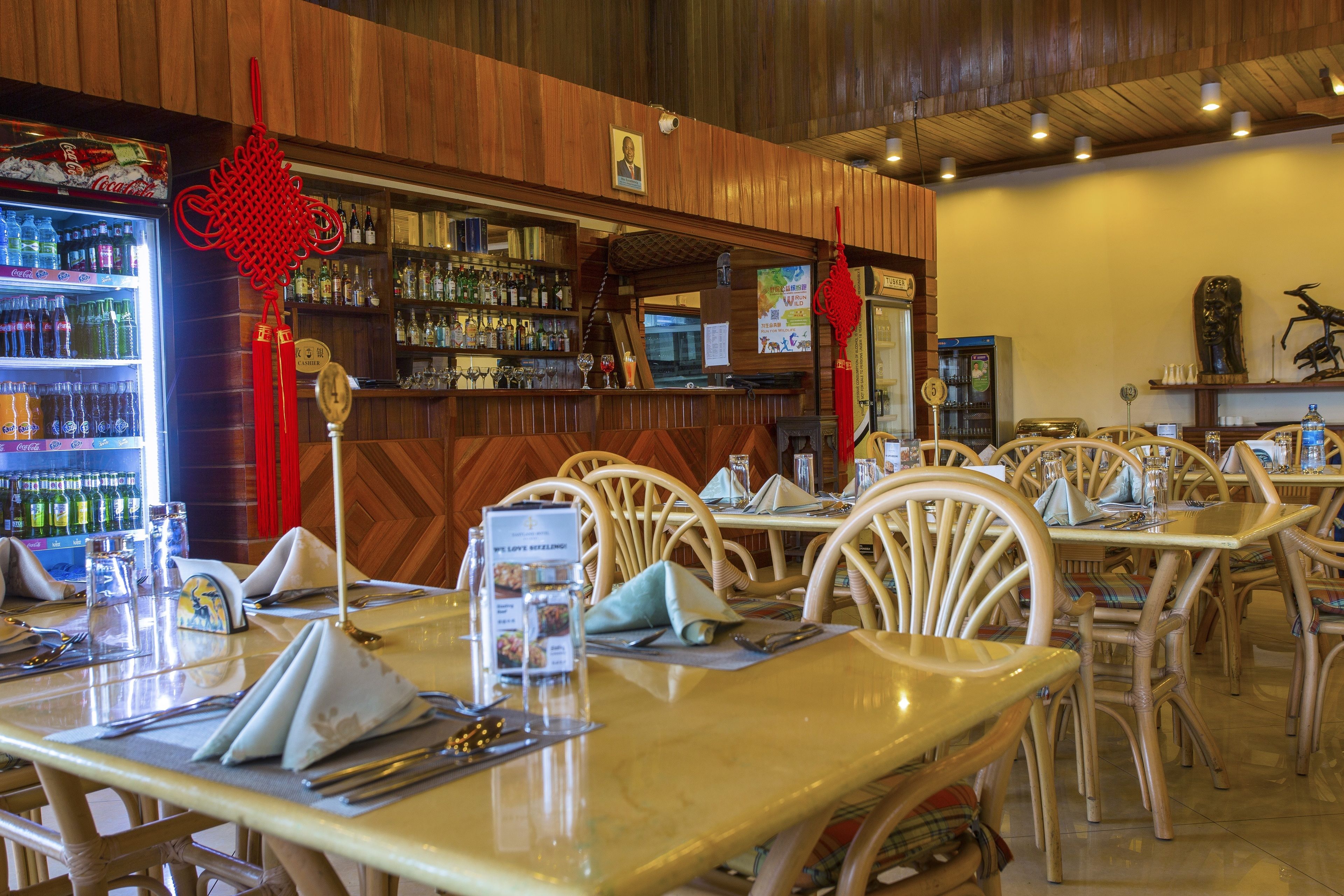Interior de restaurante con paneles de madera, zona de bar con botellas de licor y mesas y sillas ordenadas.
