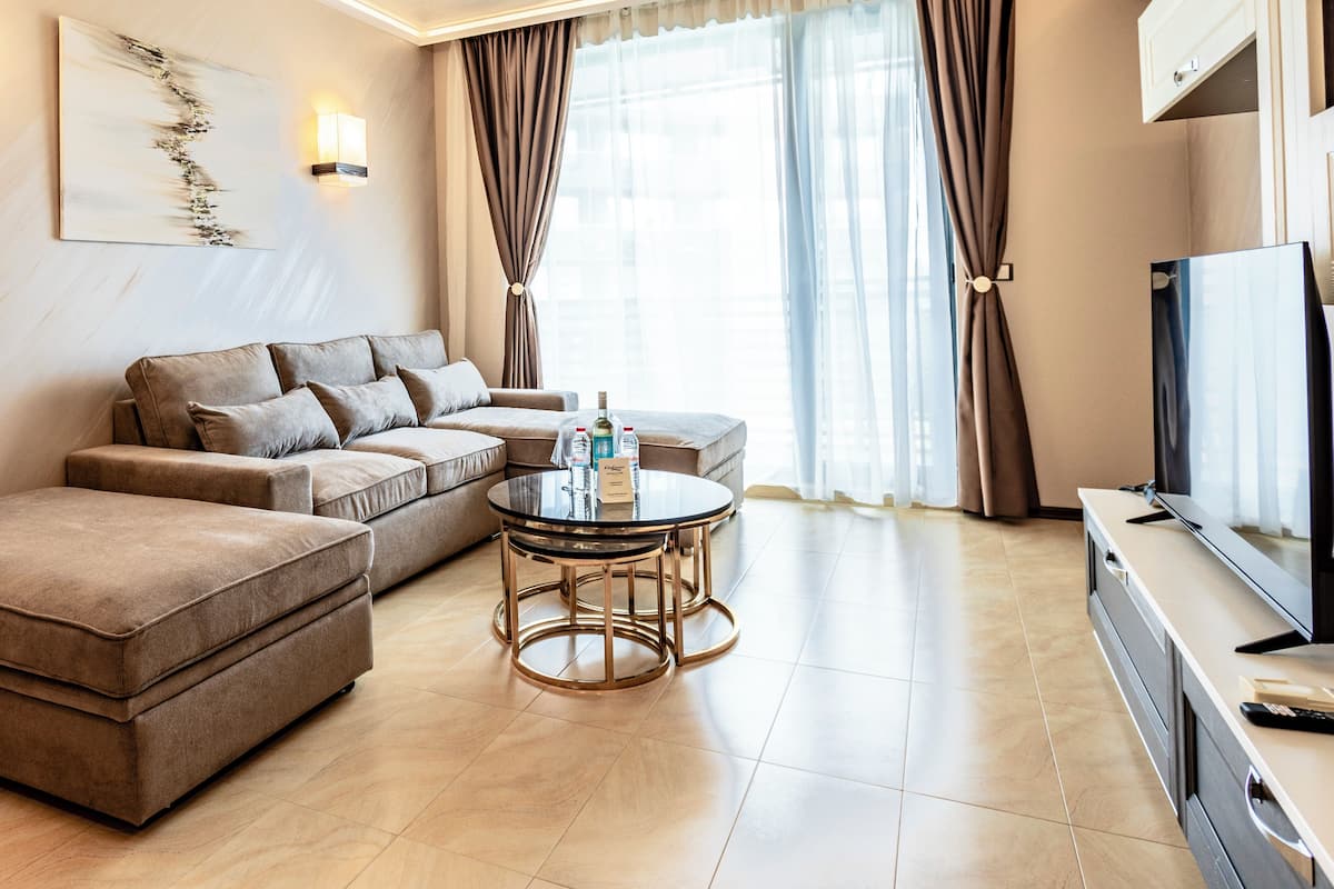 A modern living room with a sofa set, a round coffee table, and a flat-screen TV.