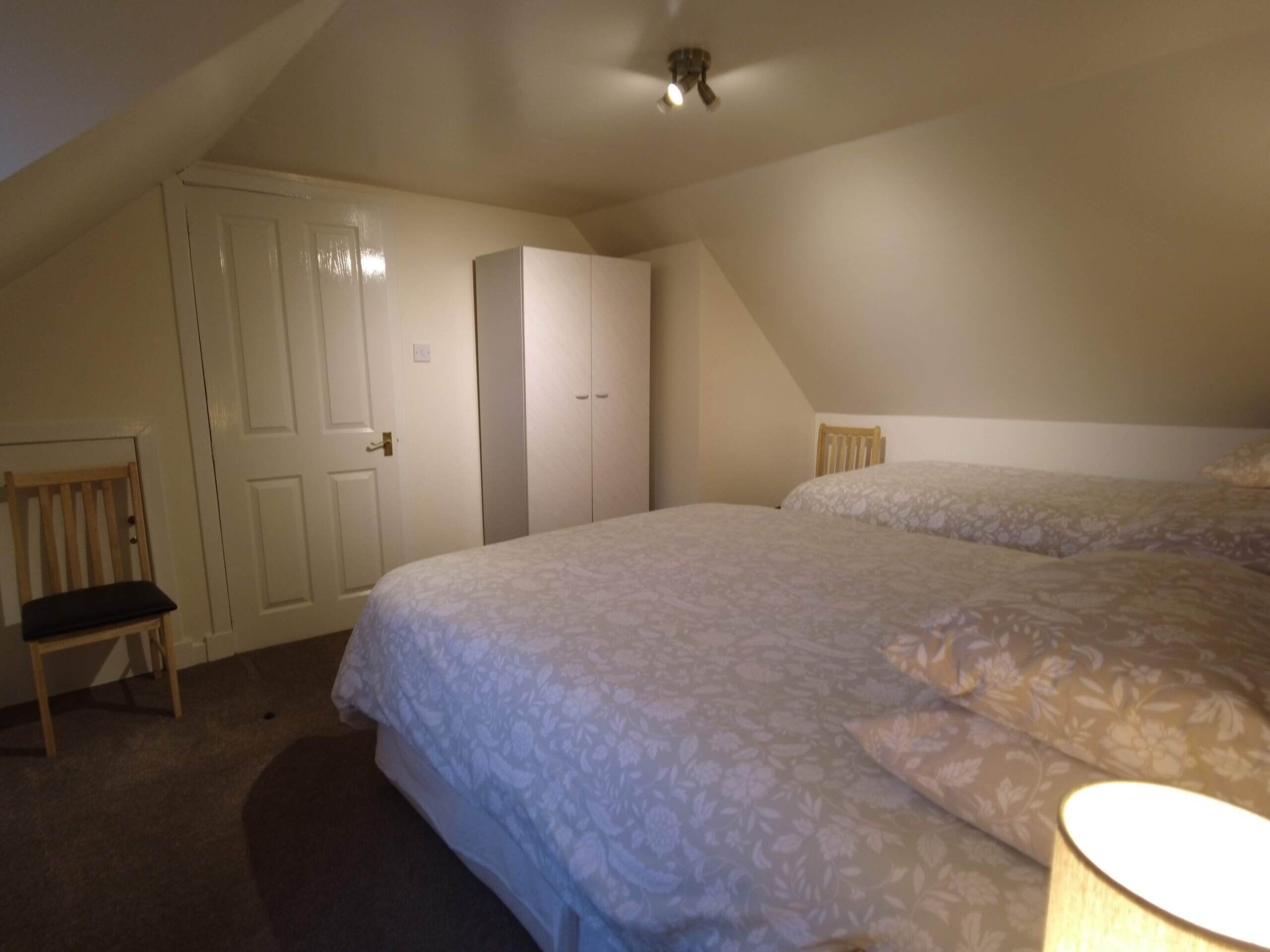 Ein Schlafzimmer mit zwei Betten, einem Sessel und einem Kleiderschrank.