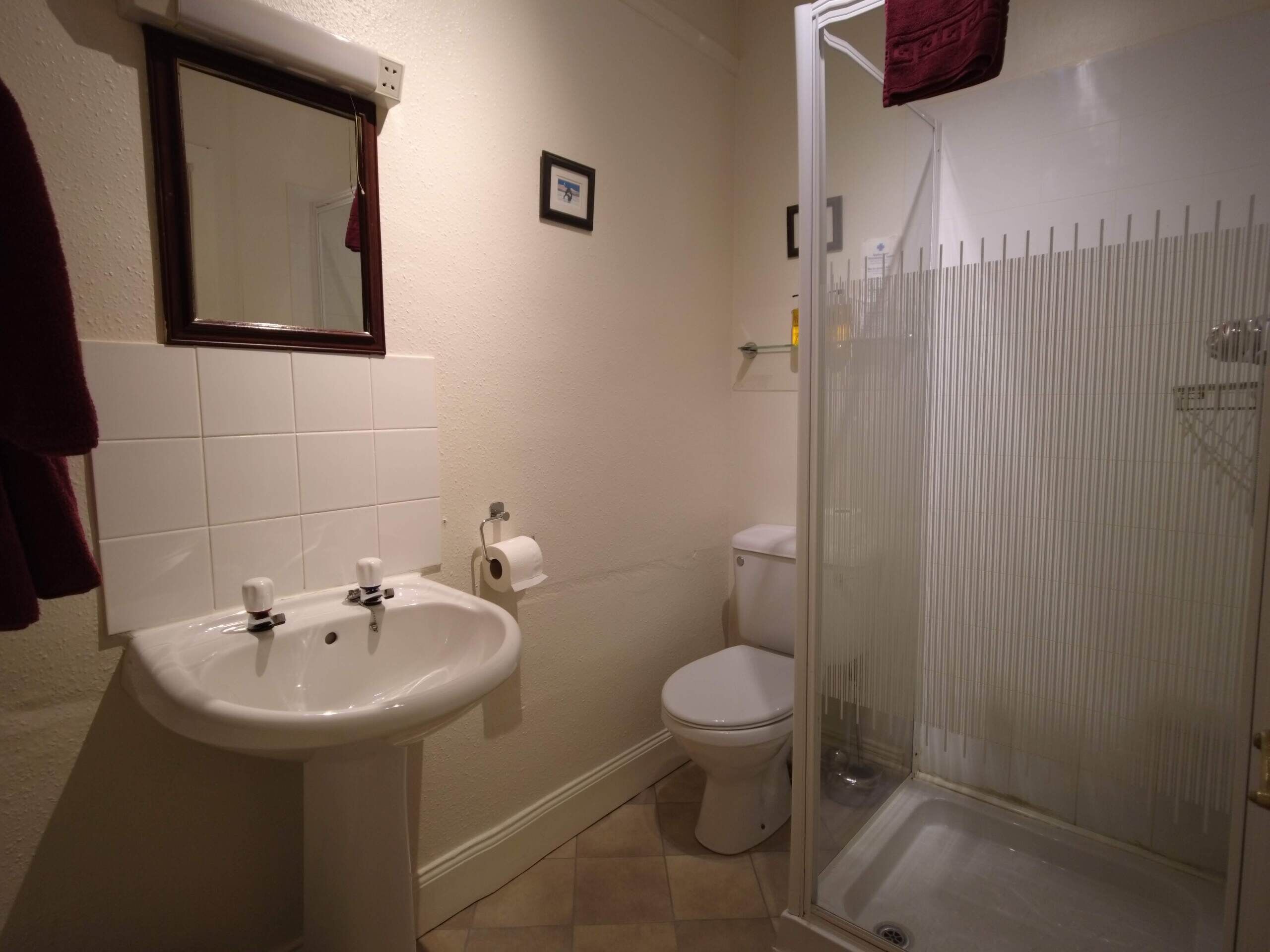 Un baño con lavamanos, inodoro y cabina de ducha de vidrio.