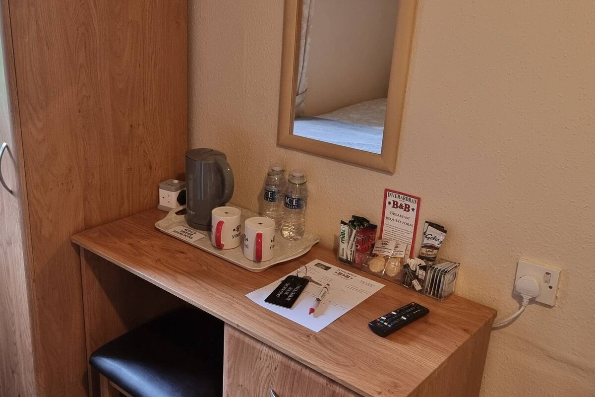 A small kitchenette with a coffee maker, water bottles, a mirror, and a sign for Interland B&B.
