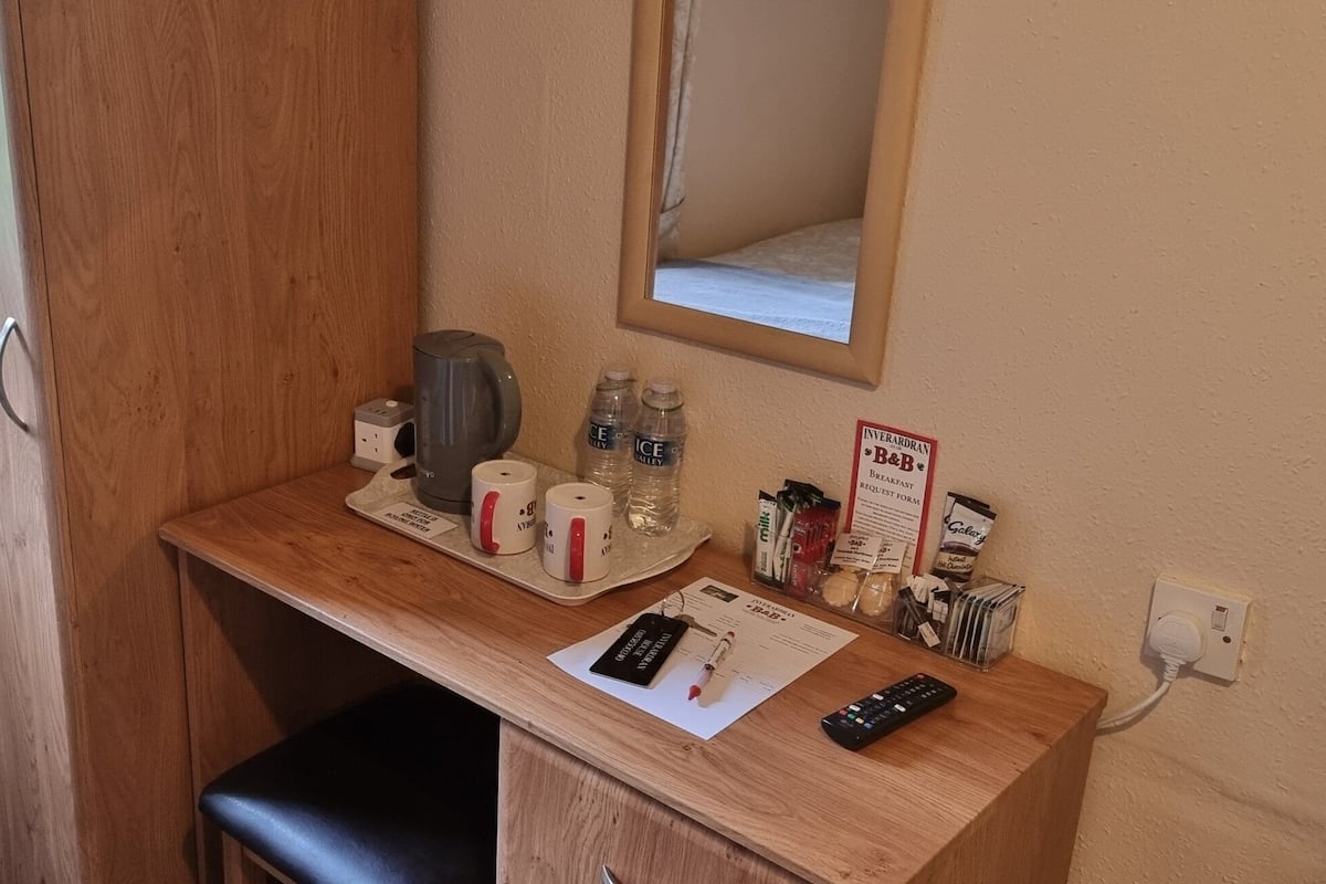 A small kitchenette with a coffee maker, water bottles, a mirror, and a sign for Interland B&B.