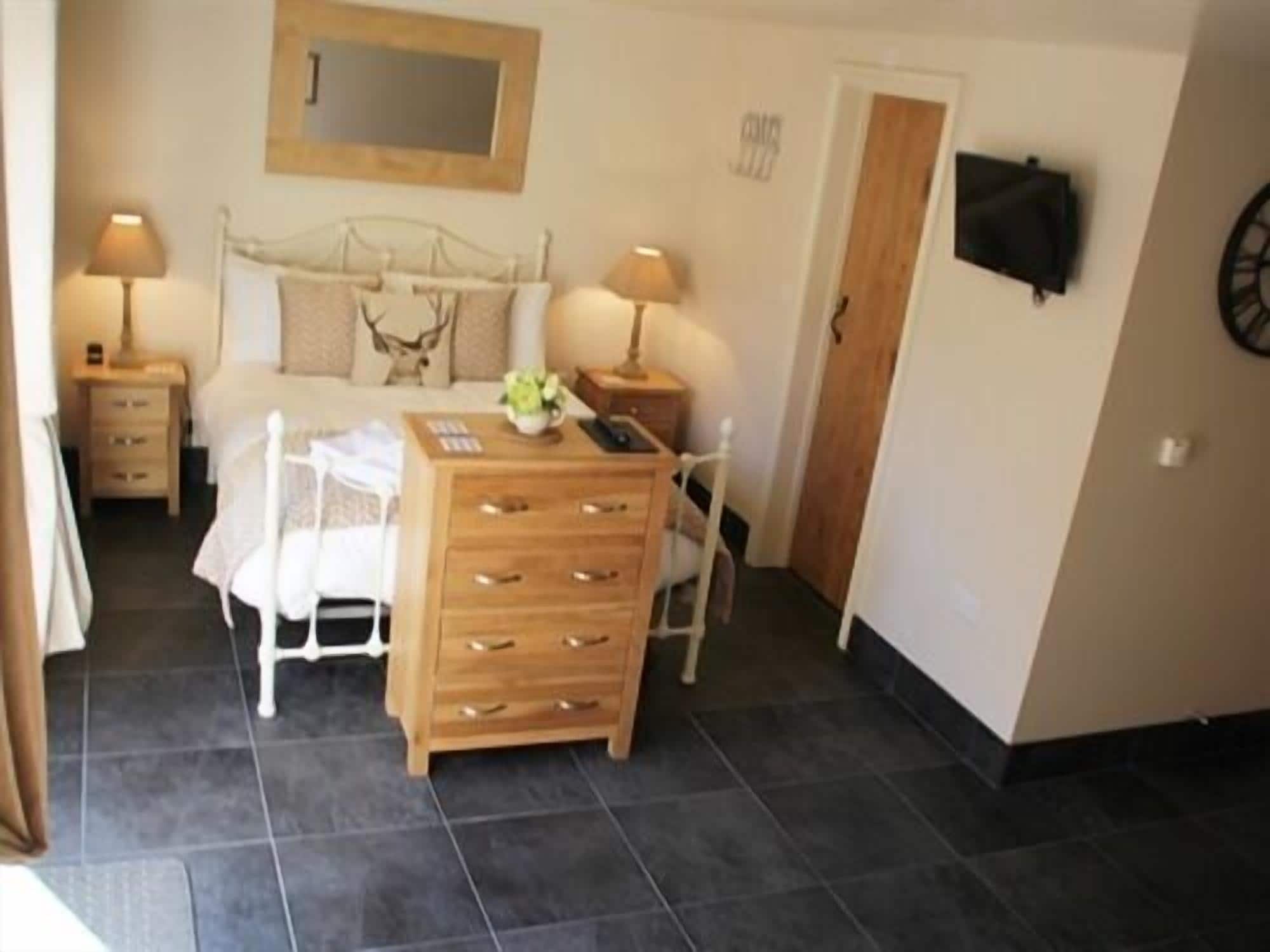 A bedroom with a bed, bedside tables, a dresser, a chair, a lamp, and a clock on the wall.