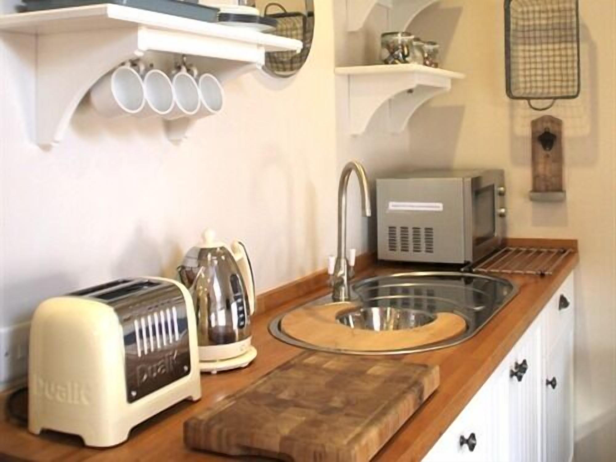 A kitchen with a toaster, kettle, and sink.