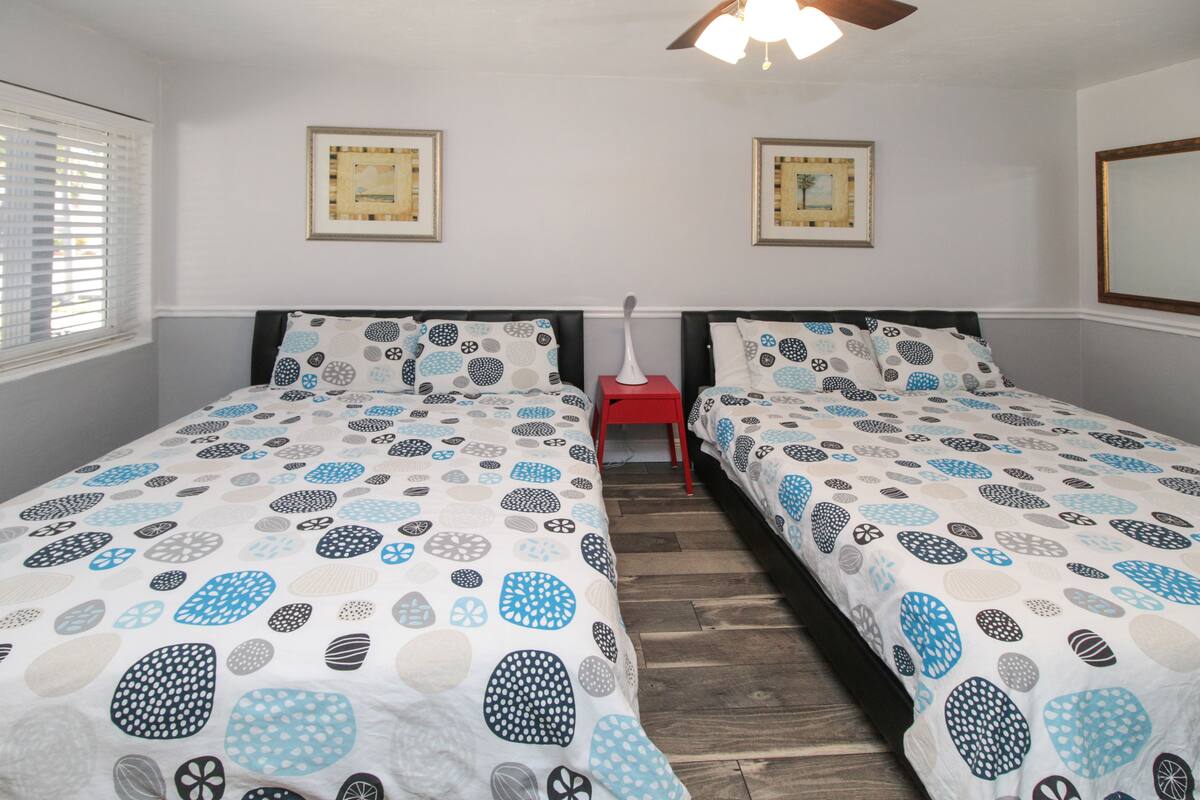A bedroom with two single beds, a wooden floor, and a ceiling fan.