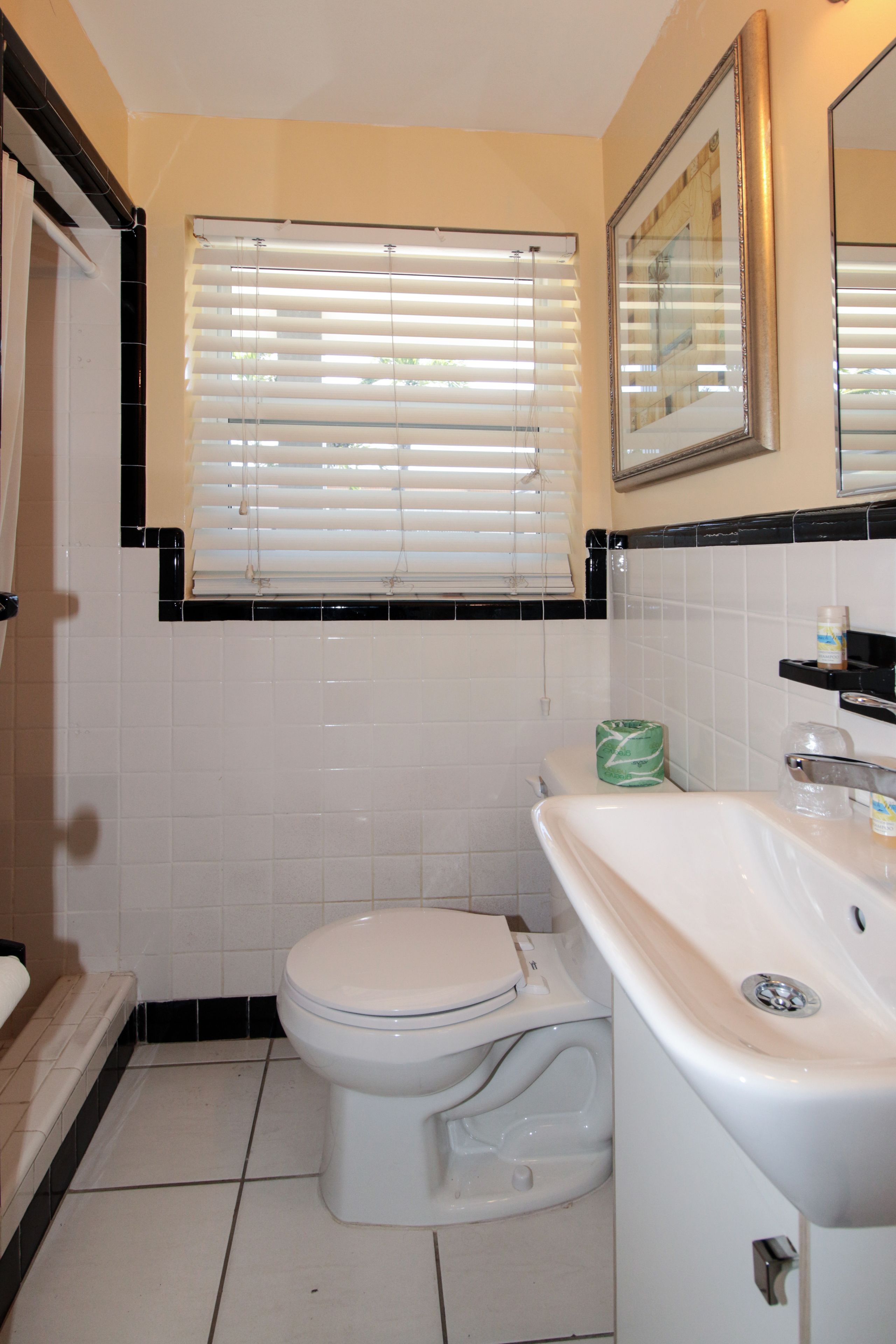 Ein Badezimmer mit Toilette, Waschbecken und einem Fenster mit Jalousien.
