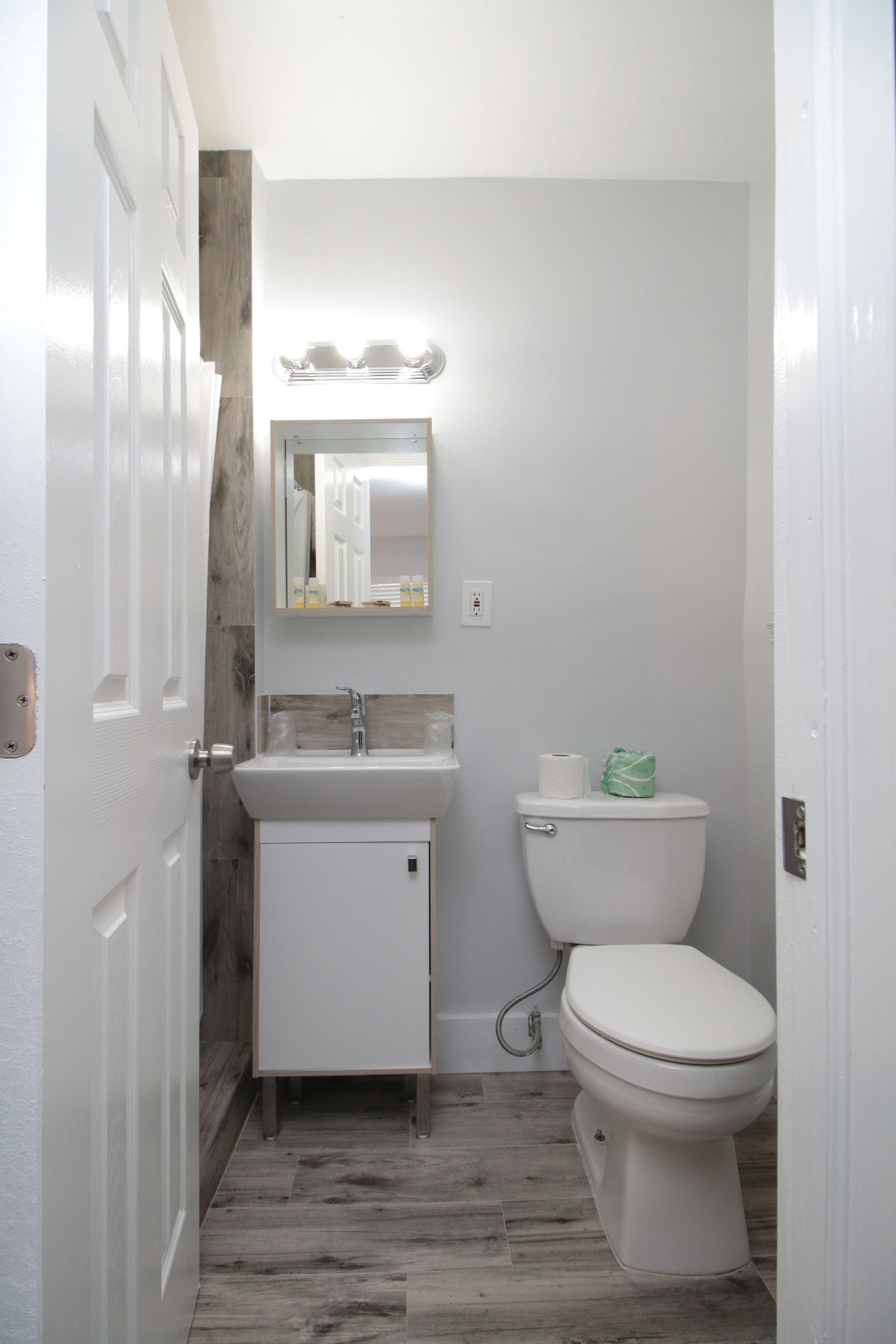 Een badkamer met een wit wastafel, een toilet en een spiegel boven het wastafel.
