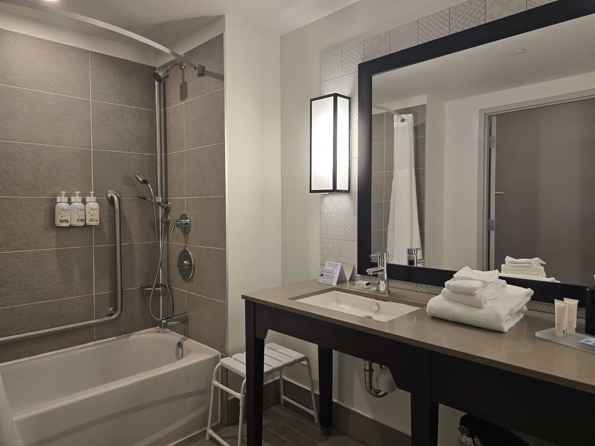 Een moderne badkamer met een badkuip, douche, wastafel en een grote spiegel.