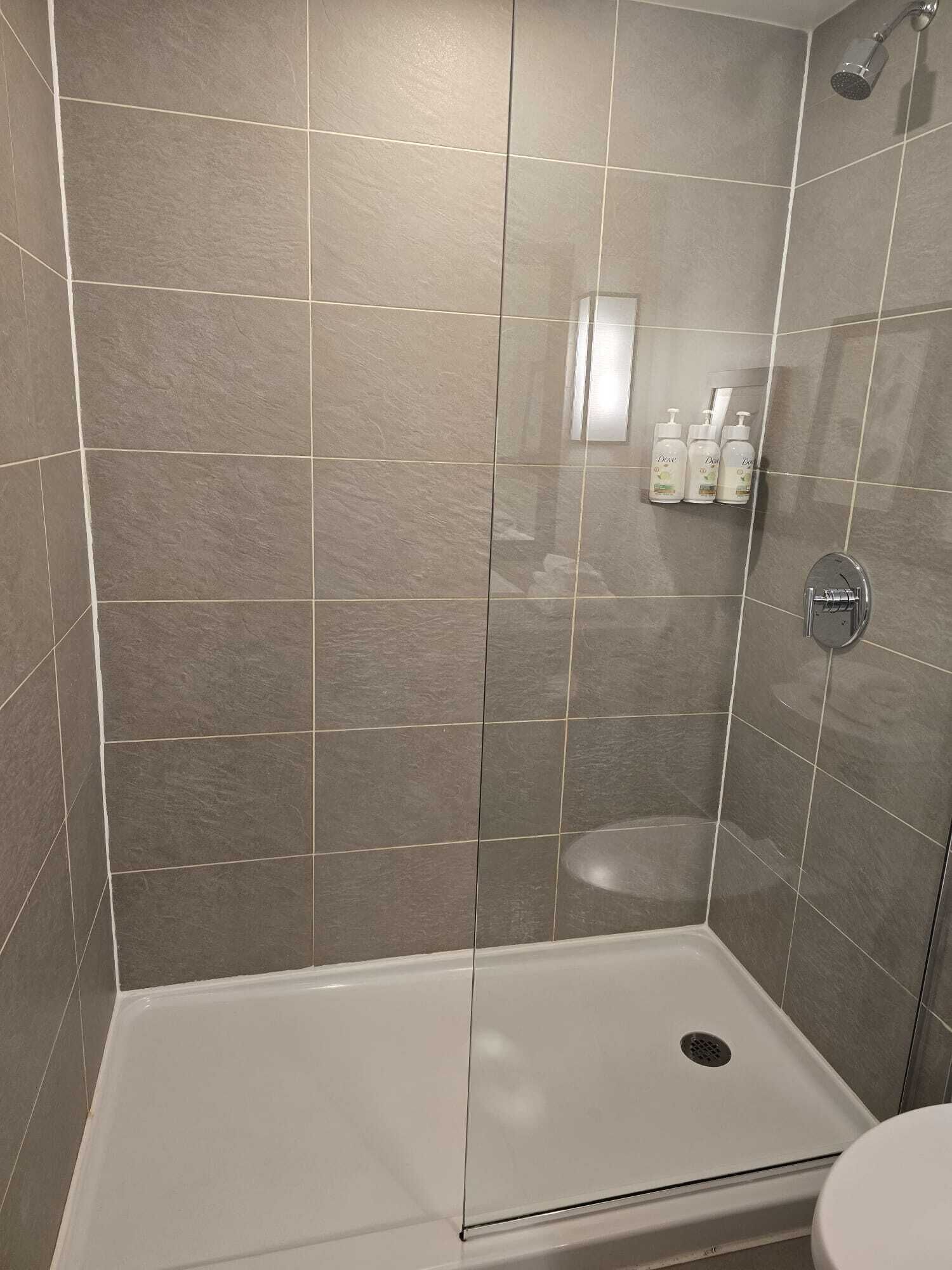 A shower with a glass door, a white bathtub, and a toilet.