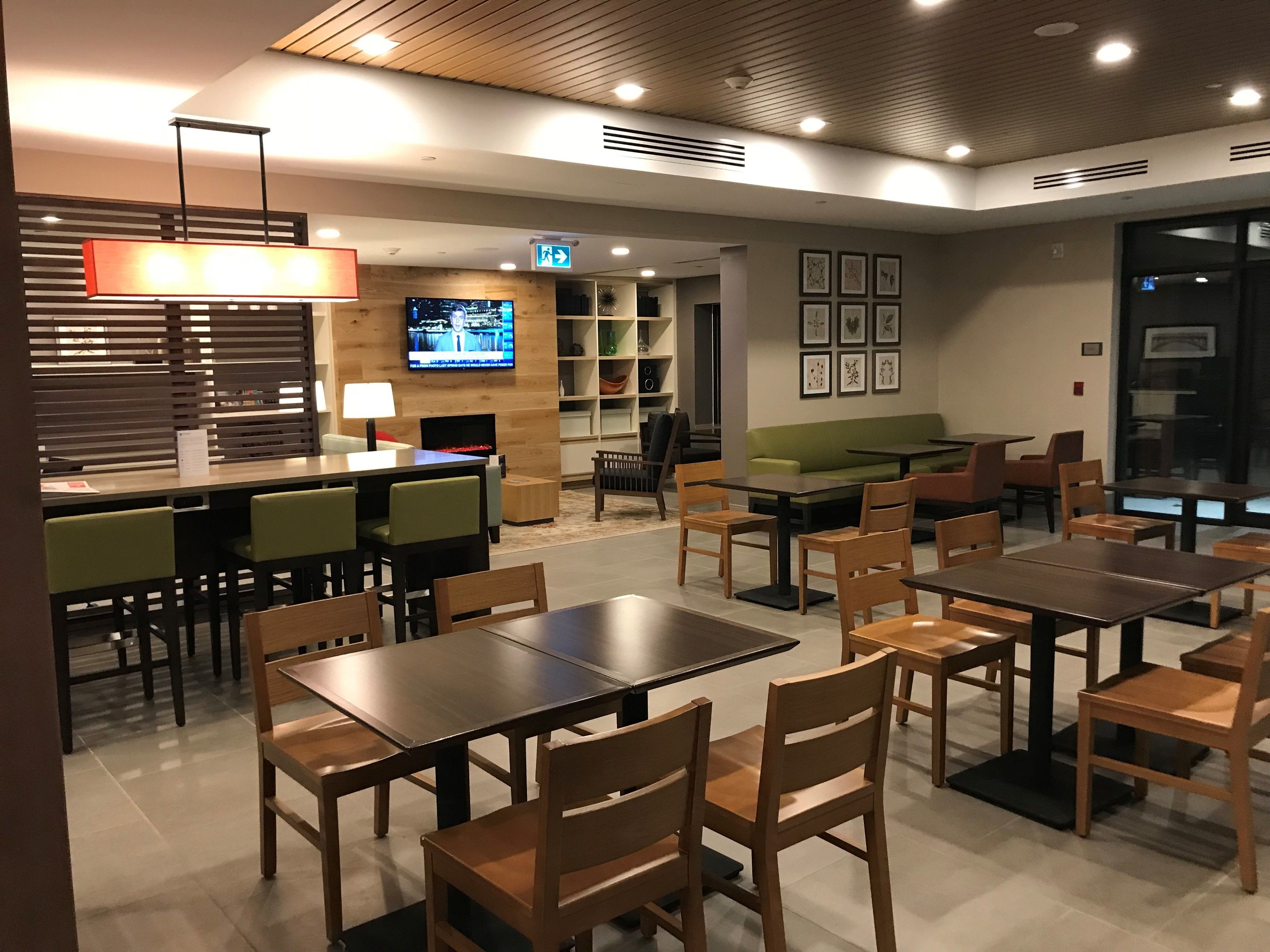 A modern cafe with wooden furniture, a TV screen, and a green sofa.