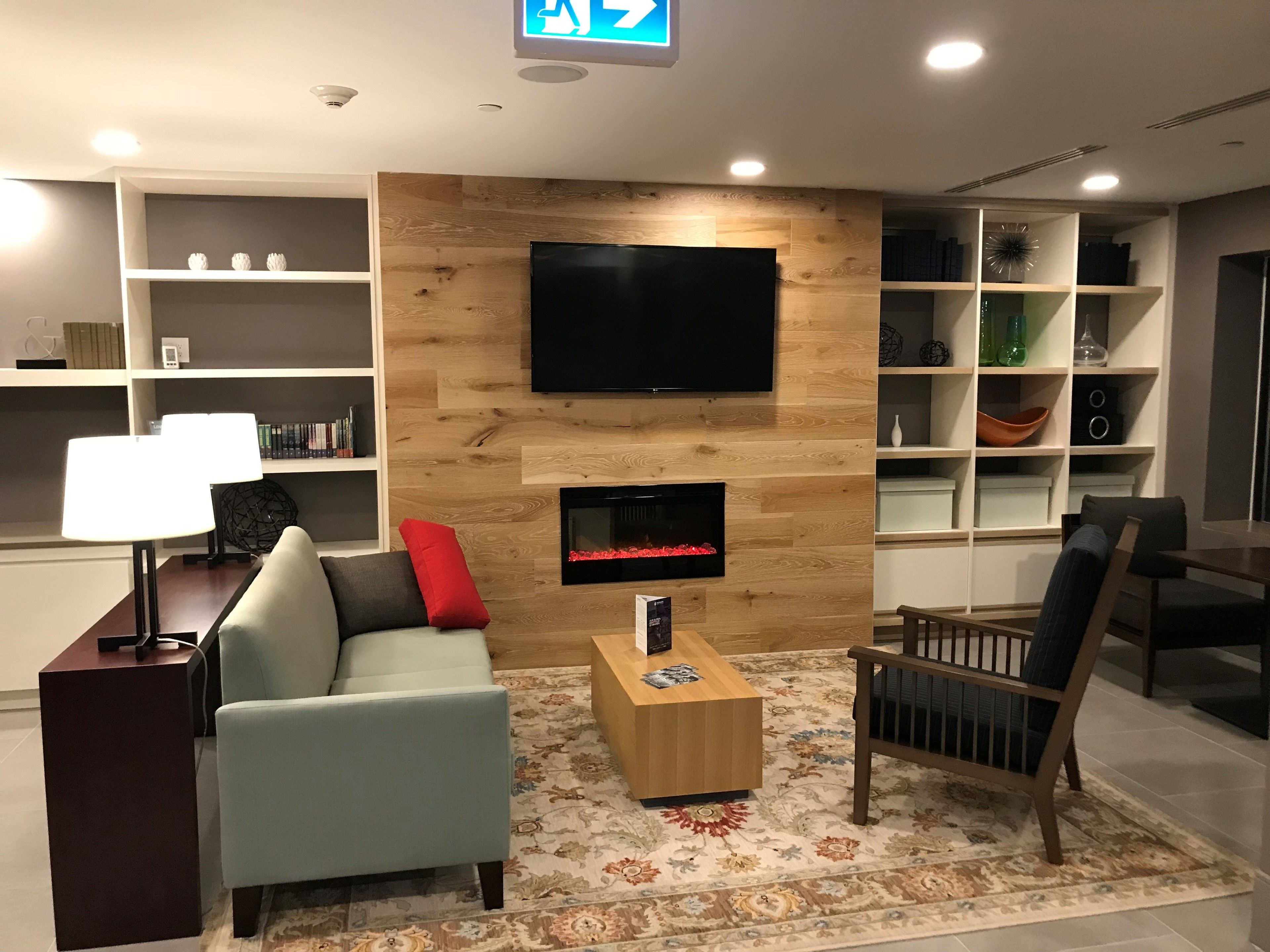 Un salon moderne doté d’un téléviseur à écran plat, d’une cheminée, d’un canapé, d’une table basse et d’une bibliothèque.
