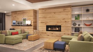 A modern living room with green sofas, a fireplace, a wooden wall, and a bookshelf. - Country Inn & Suites by Radisson, Belleville, ON (Belleville)