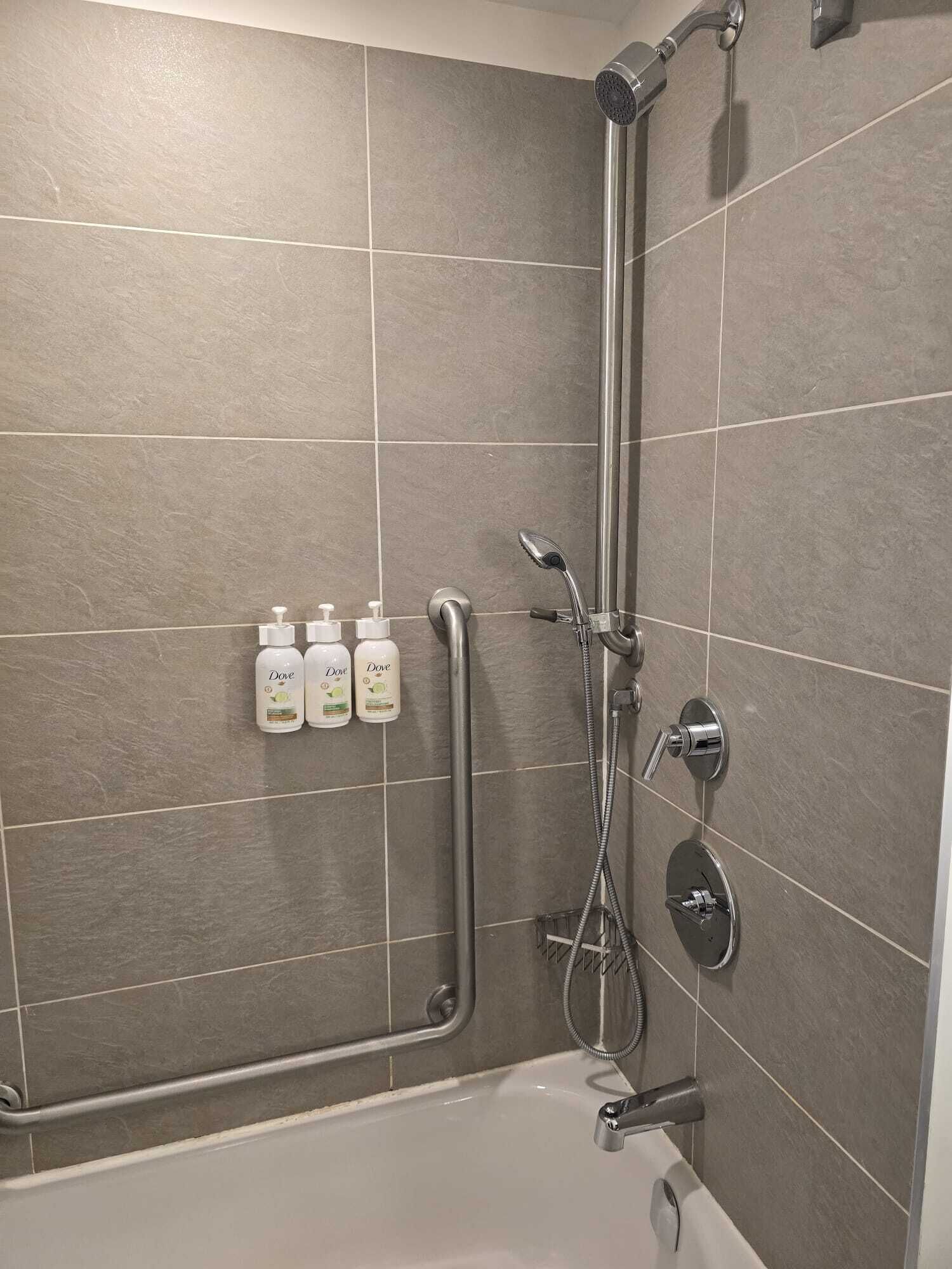 Et moderne badeværelse med bruser, badekar og tre Dove sæber hængende på væggen.
