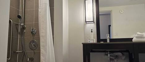 Un baño con bañera, ducha y tocador con espejo.