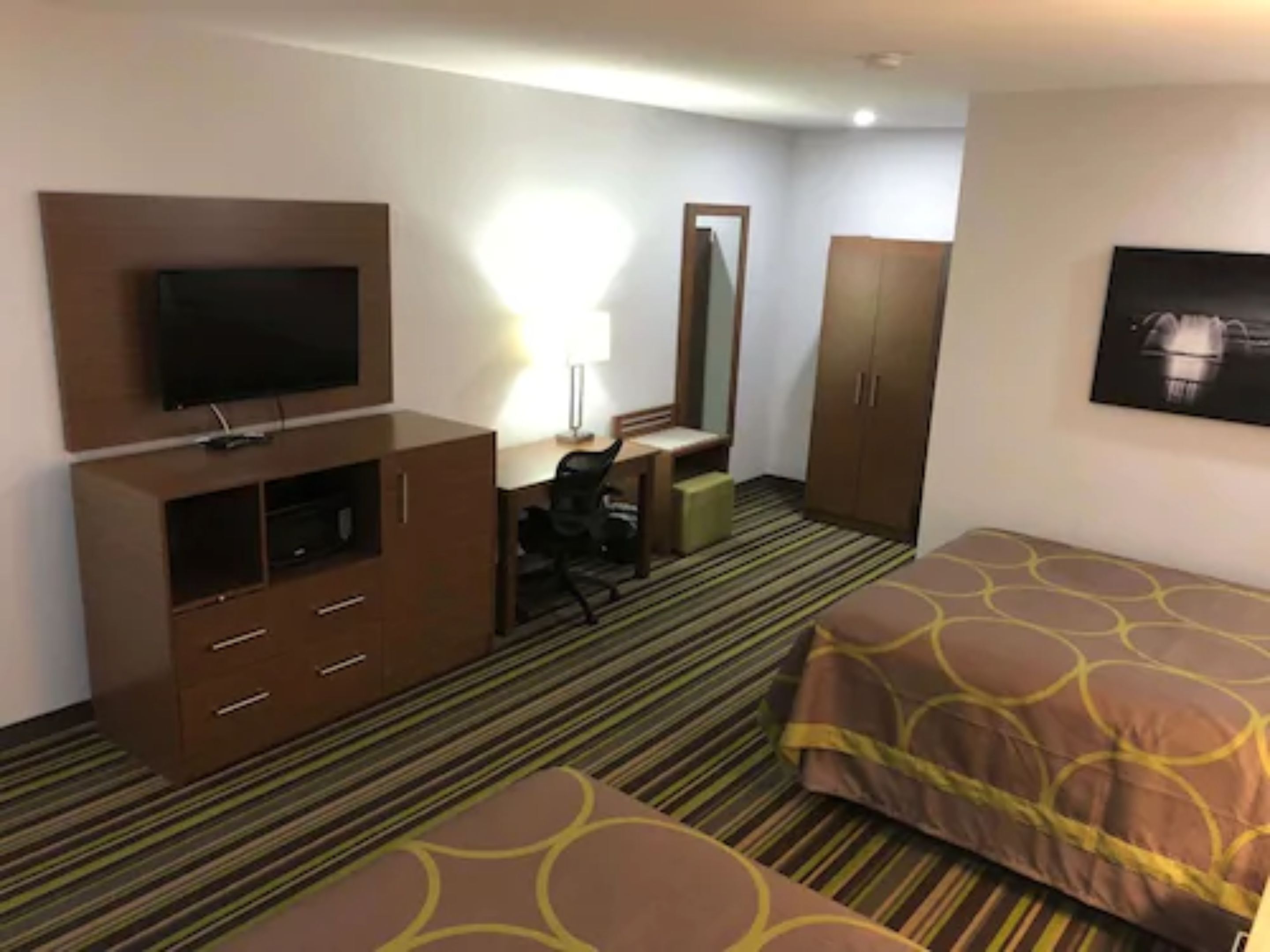 Ein Hotelzimmer mit einem Bett, einem Schreibtisch, einem Sessel, einem Fernseher und einem Kleiderschrank.