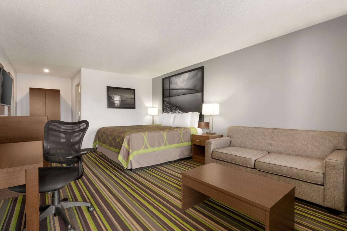 Una habitación de hotel con una cama, un sofá, un escritorio, una silla y una lámpara.
