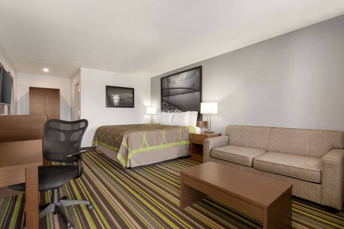 Una habitación de hotel con cama, sofá, escritorio y silla.