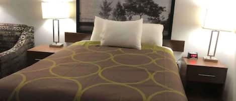 A hotel room with a bed, two bedside tables, a lamp, a chair, and a cityscape view.