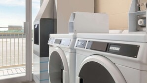 A modern laundry facility with two front-loading washing machines, a coin return slot, and a control panel.