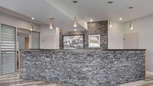 A modern kitchen with a granite island, pendant lights, and a stone backsplash.