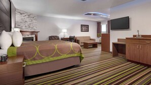 A hotel room with a bed, a desk, a chair, a sofa, a TV, and a wardrobe.