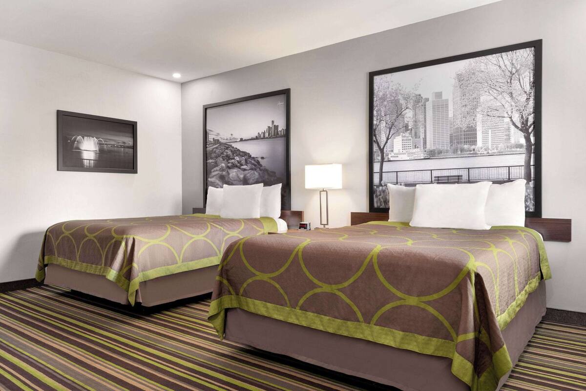 Habitación de hotel con dos camas, vista panorámica de la ciudad y un cuadro en la pared.