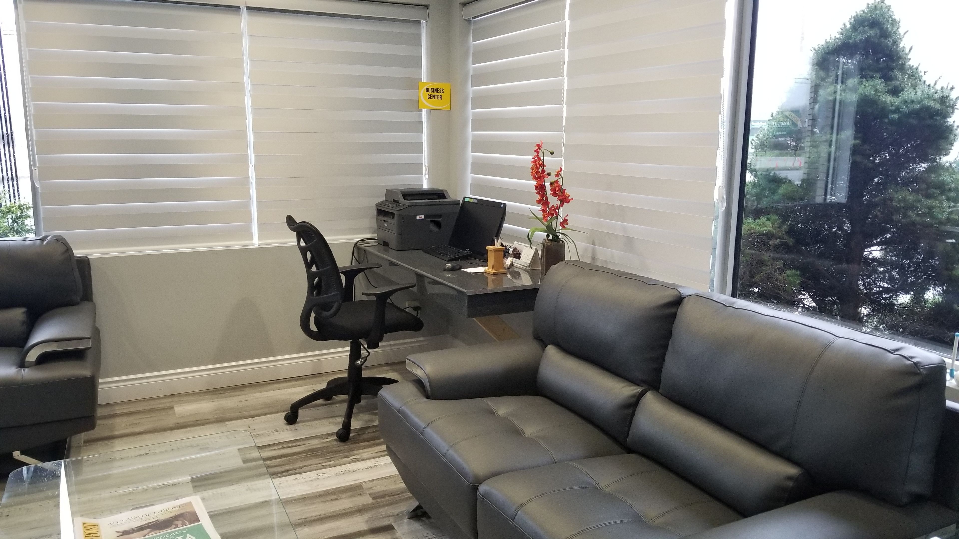 Un bureau d’angle équipé d’un bureau, d’une chaise et d’un canapé. On peut voir une enseigne « Centre d’affaires » sur le mur.