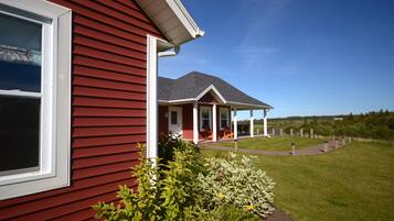 A red house with a porch and a lawn.
