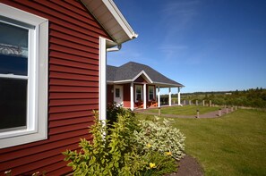 A red house with a porch and a lawn. - The Gables of PEI (Stanley Bridge)