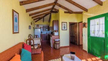 Una sala acogedora con un sofá, una mesa de comedor y una cocina al fondo.