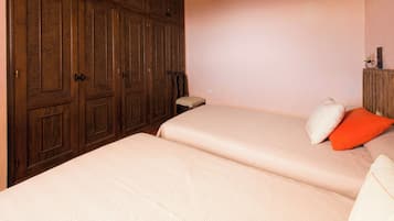 Un dormitorio con dos camas, armarios de madera y una mesita de noche pequeña.